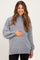 woman wearing a gray maternity sweater with a high neck and long sleeves, holding her baby bump