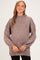 woman wearing a mauve maternity sweater with a high neck and balloon sleeves, showcasing her baby bump