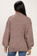 woman wearing a brown oversized knit sweater with a high neckline and balloon sleeves, viewed from the back