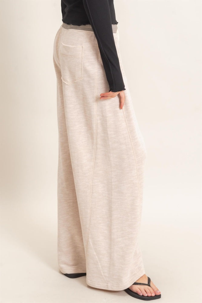 woman wearing light beige wide-leg pants with a high waist and back pockets, styled casually with a long sleeve top