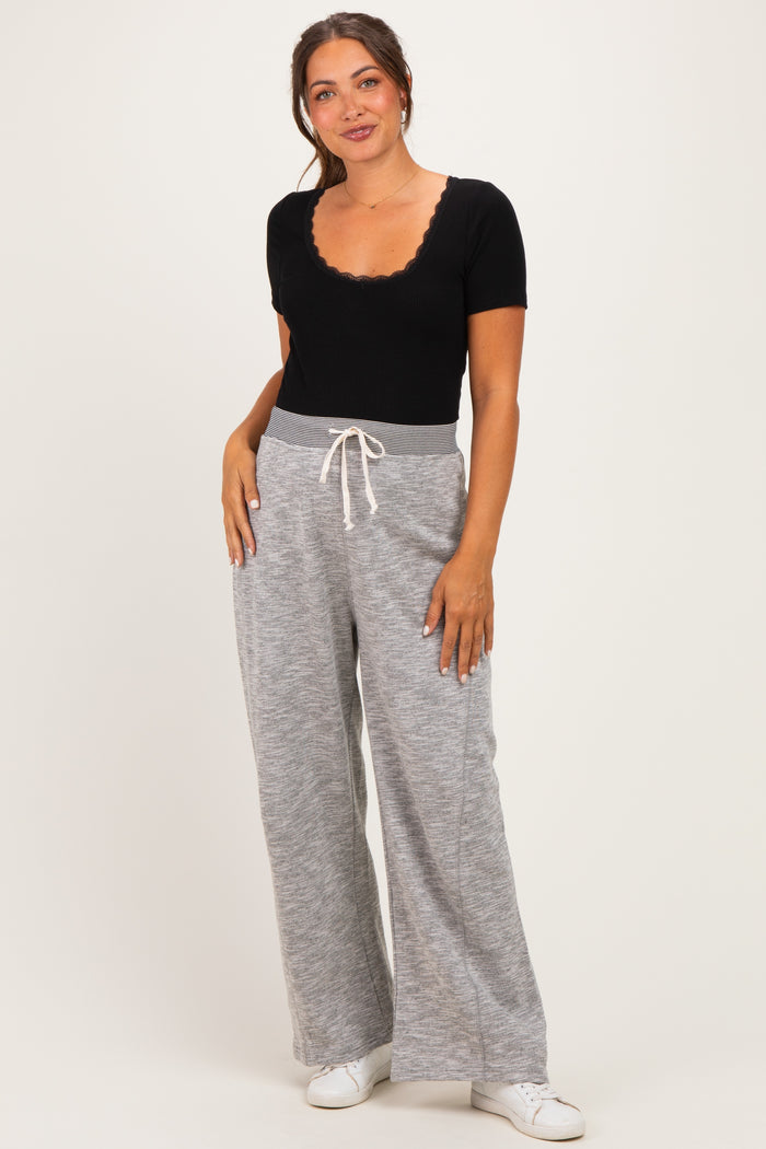 woman wearing a black ribbed maternity top and grey wide-leg pants with a drawstring waistband