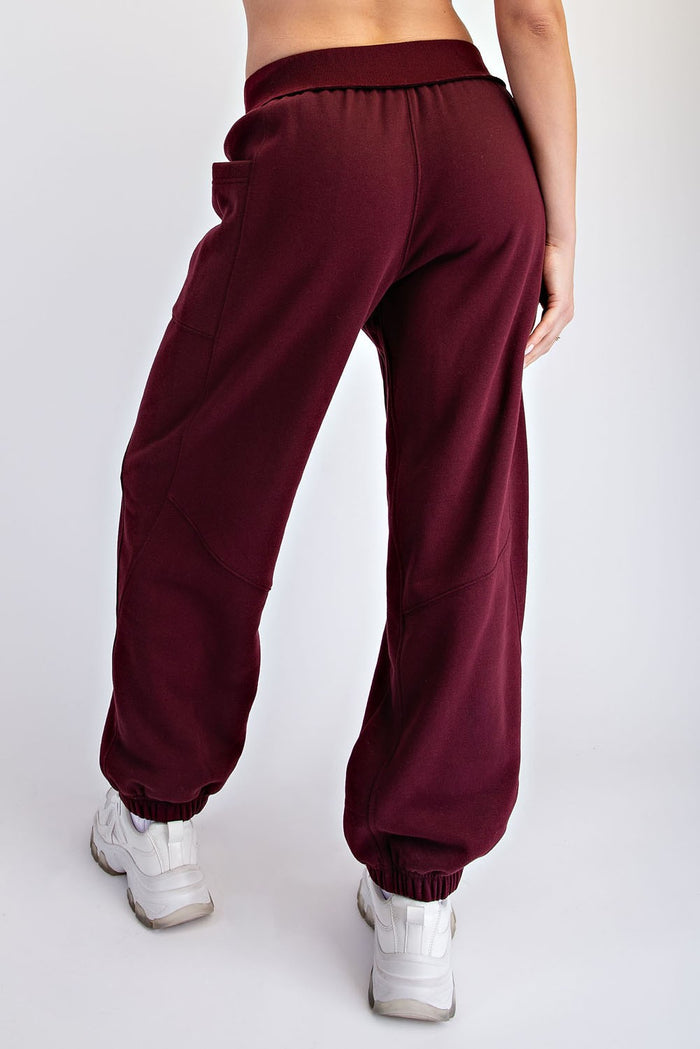 woman wearing burgundy jogger pants with an elastic waistband and cuffed ankles, seen from the back