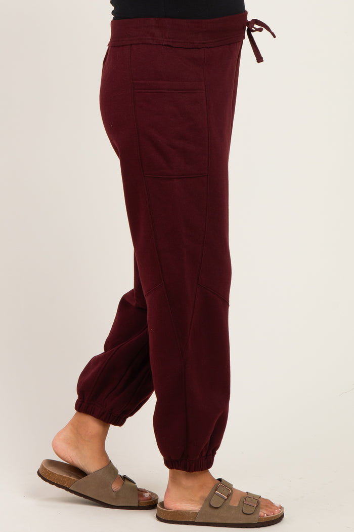 maternity wear burgundy jogger pants with elastic cuffs and drawstring waistband, model wearing sandals