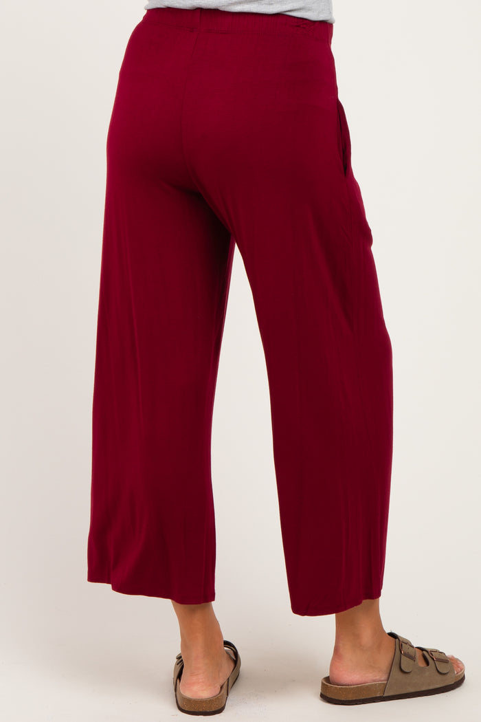 woman wearing burgundy maternity wide leg pants with pockets and sandals, seen from the back