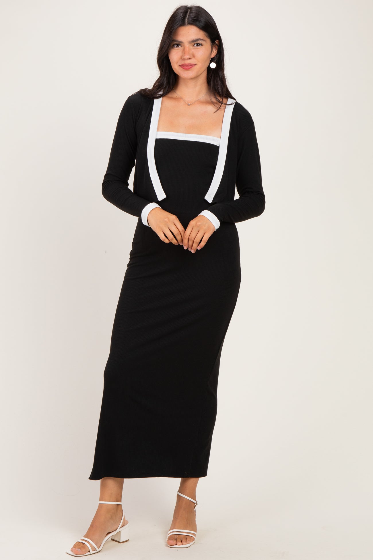 woman wearing a black long sleeve maxi dress with white strappy details and a square neckline