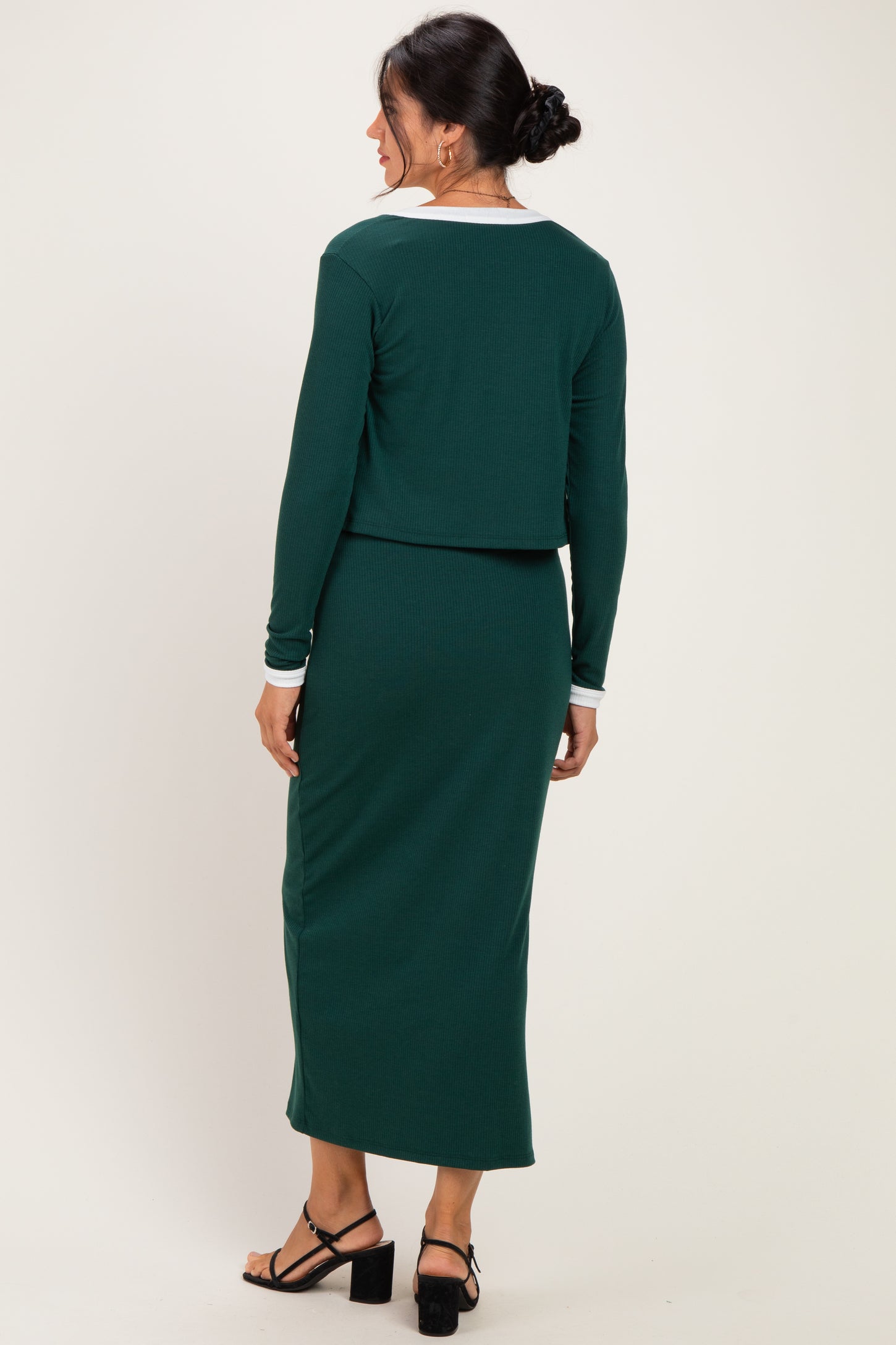 woman wearing a green ribbed two-piece dress with a cropped top and long skirt, showing the back view