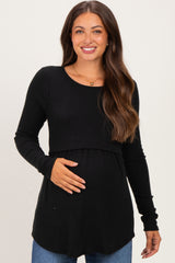 woman wearing a black long sleeve maternity top and holding her baby bump