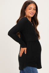 woman wearing a black long sleeve maternity top with a fitted waist and baby bump visible