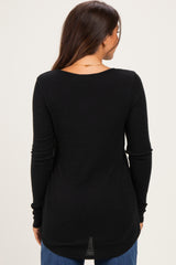 woman wearing a black ribbed maternity top, showing the back view, with long sleeves and a relaxed fit