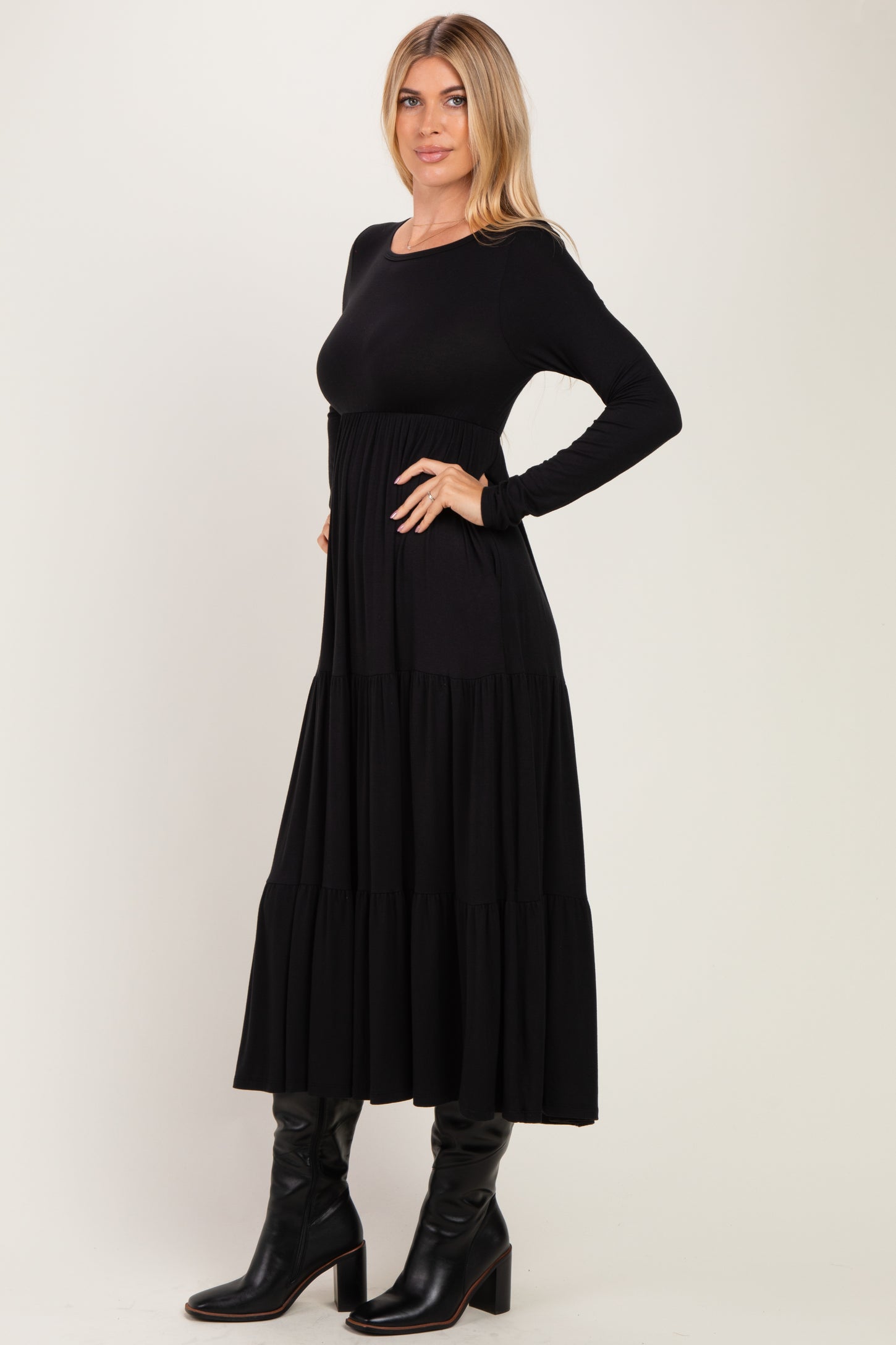 woman wearing a black long sleeve tiered maxi dress with a fitted bodice and flowing skirt