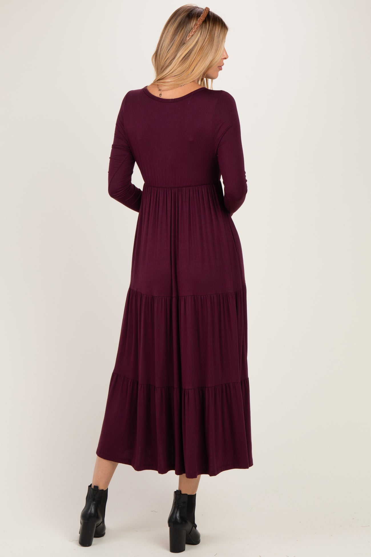 woman wearing a long burgundy tiered maxi dress with long sleeves and a fitted bodice, shown from the back