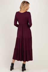 woman wearing a long burgundy tiered maxi dress with long sleeves and a fitted bodice, shown from the back