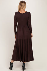 woman wearing a dark chocolate brown long sleeve maxi dress with a tiered skirt, viewed from the back