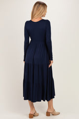 woman wearing a navy long sleeve maxi dress with tiered ruffle details and a fitted bodice, viewed from the back