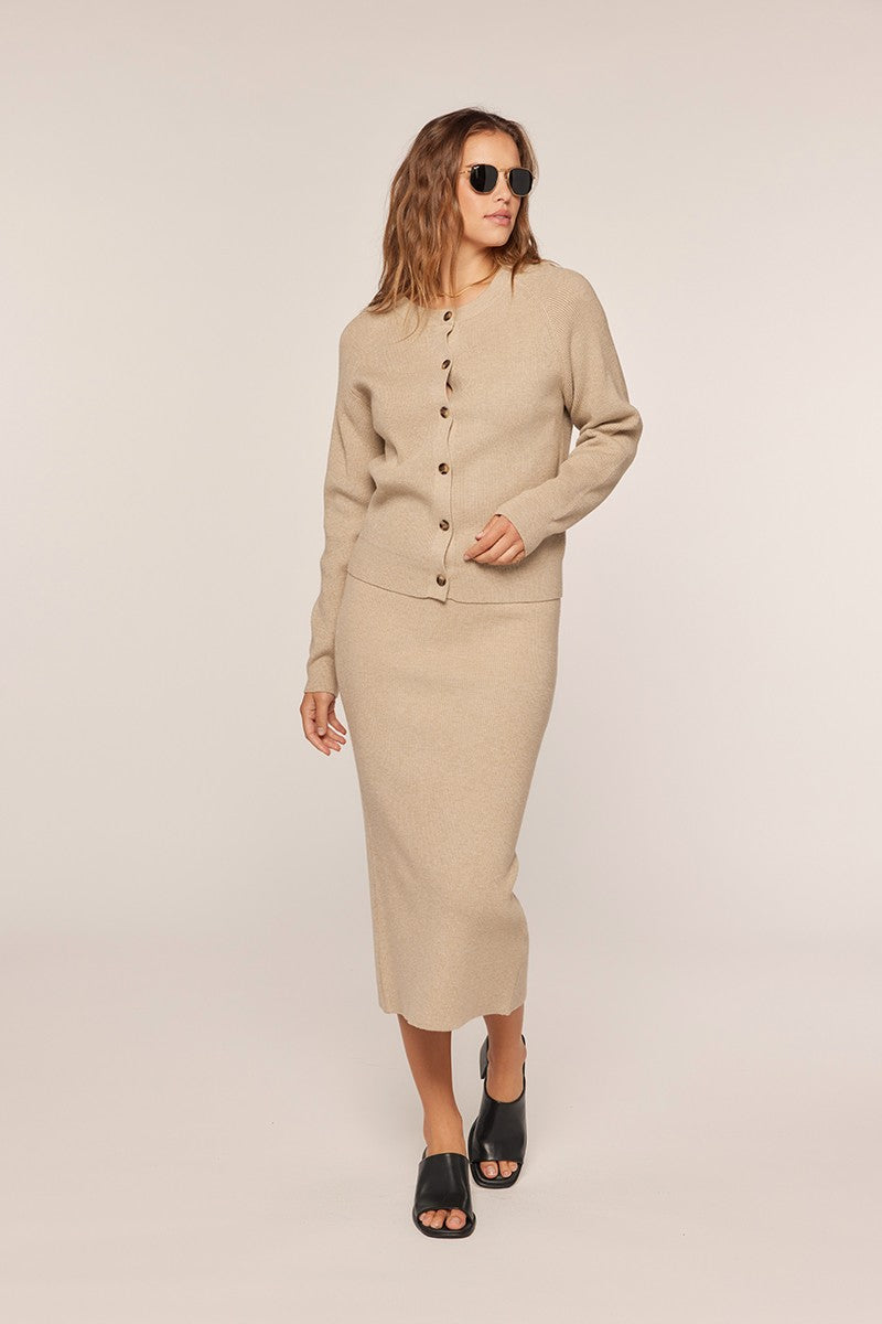 woman wearing a beige knit cardigan and matching midi skirt with black sunglasses and open-toe black sandals