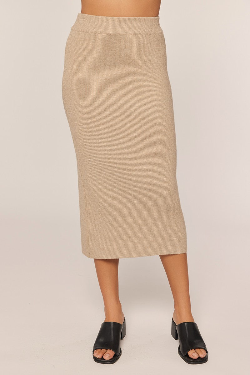 woman wearing a beige ribbed midi skirt paired with black slide sandals