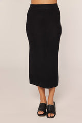 woman wearing a black ribbed midi skirt with a fitted waistband and open-toe black sandals