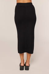 woman wearing a black ribbed midi skirt, shown from the back, with a fitted silhouette and a comfortable waistline