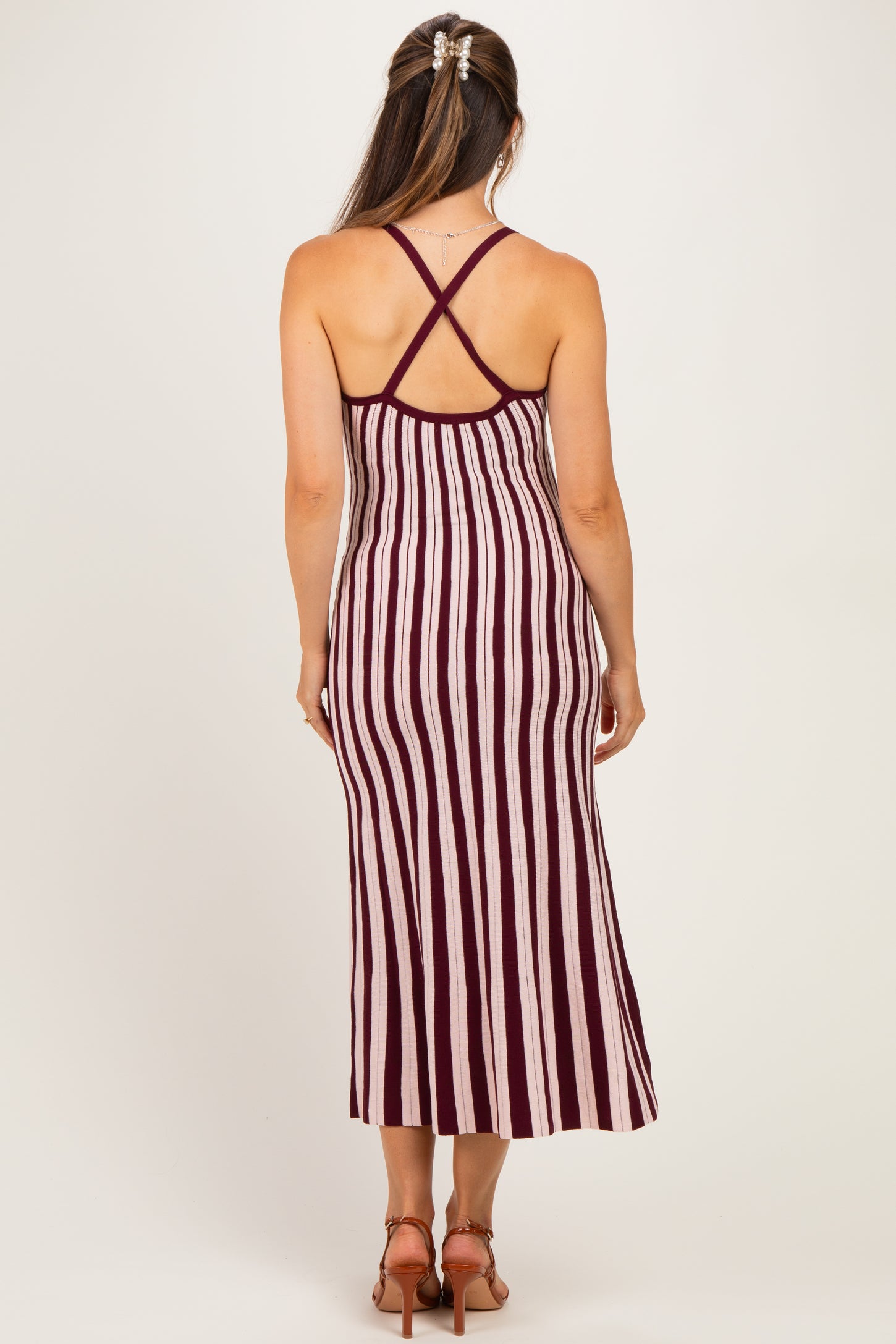 woman wearing a burgundy and cream striped maternity maxi dress with a crisscross back design
