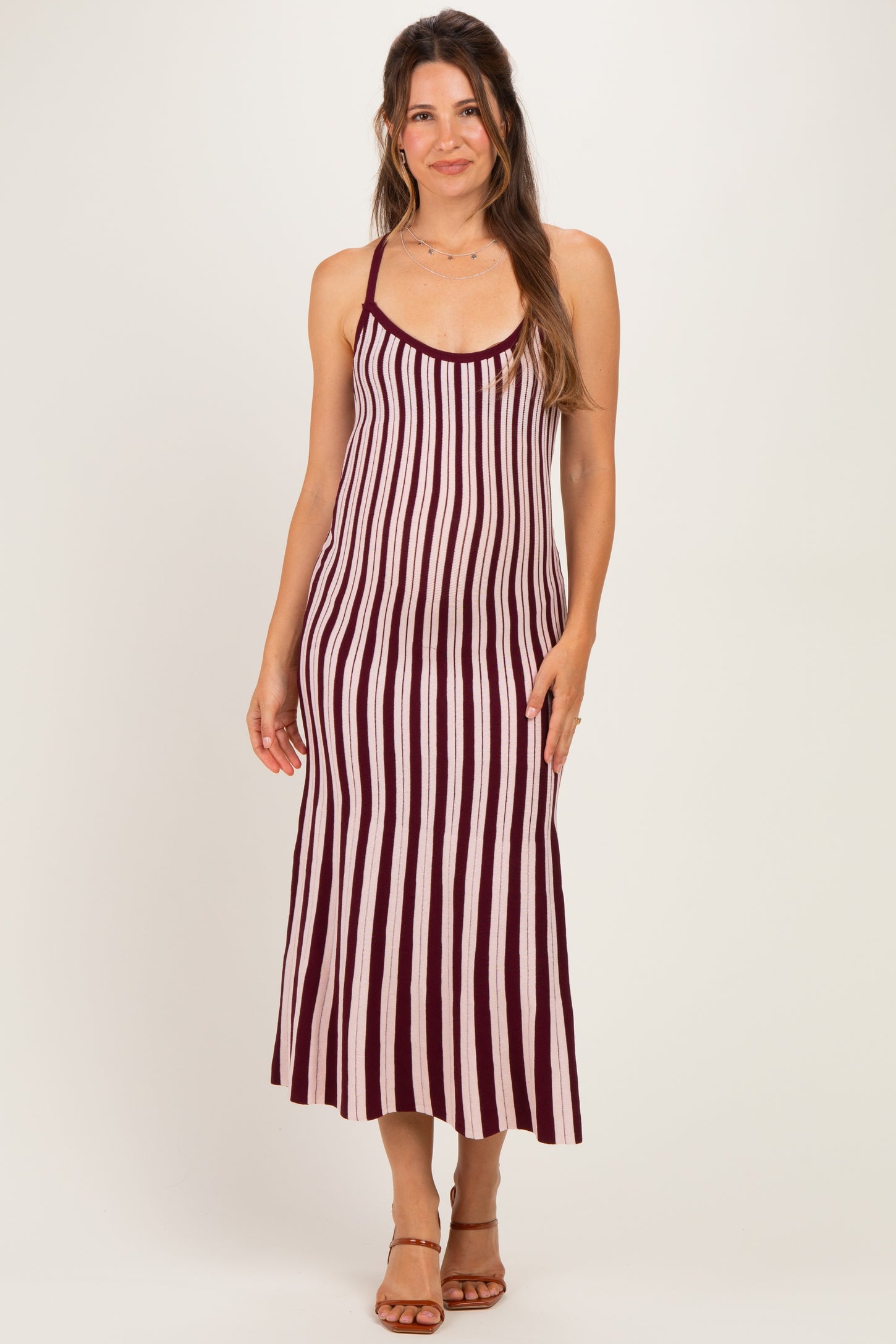 woman wearing a burgundy and cream striped maternity maxi dress with adjustable straps