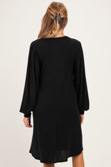 woman wearing a black ribbed maternity dress with long sleeves, viewed from the back