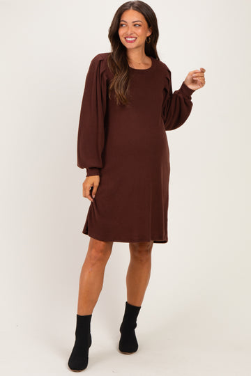 woman wearing a brown maternity dress with puff sleeves and a relaxed fit, showcasing her baby bump
