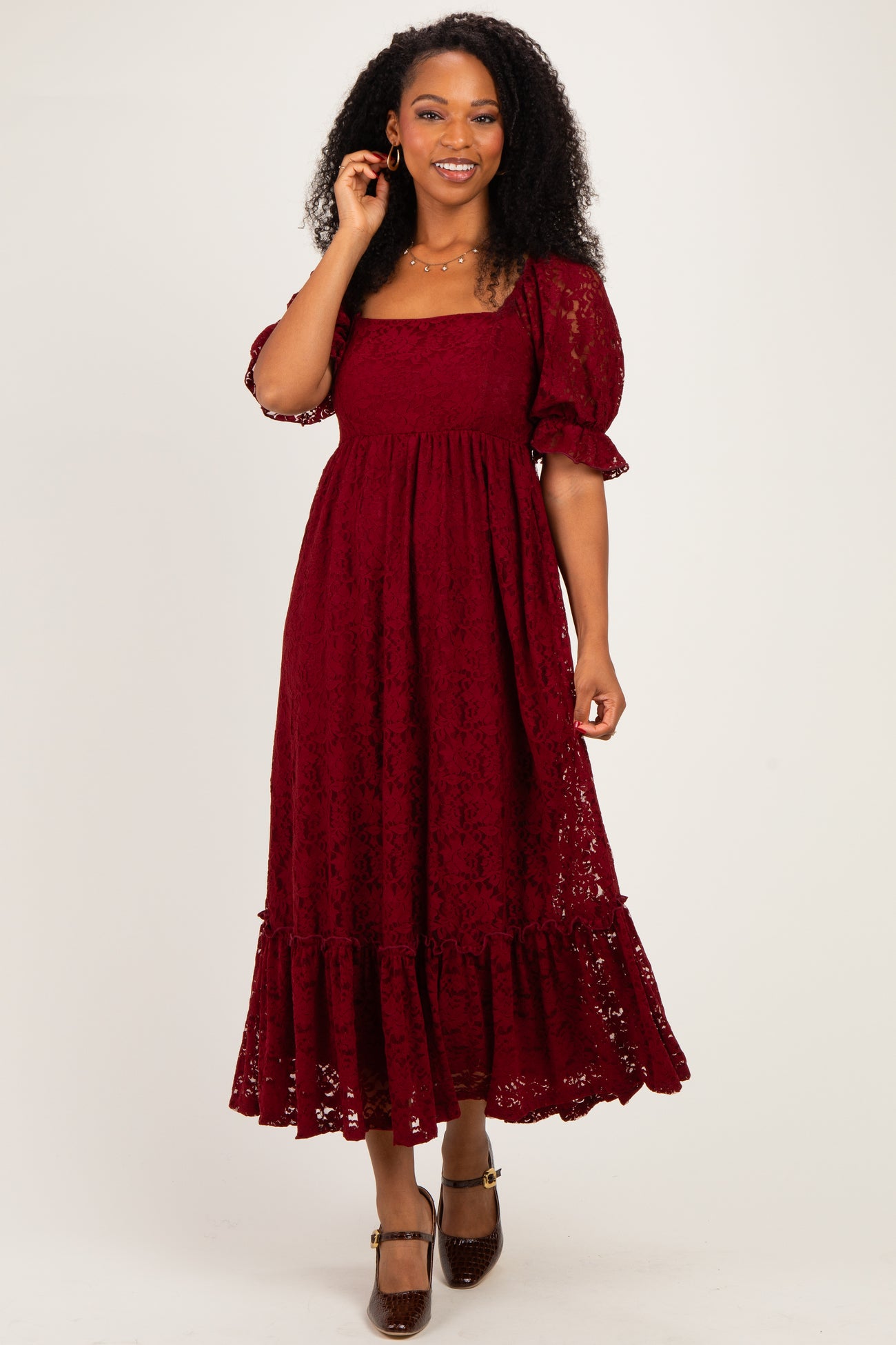 woman wearing a burgundy lace midi dress with puff sleeves and ruffle hem