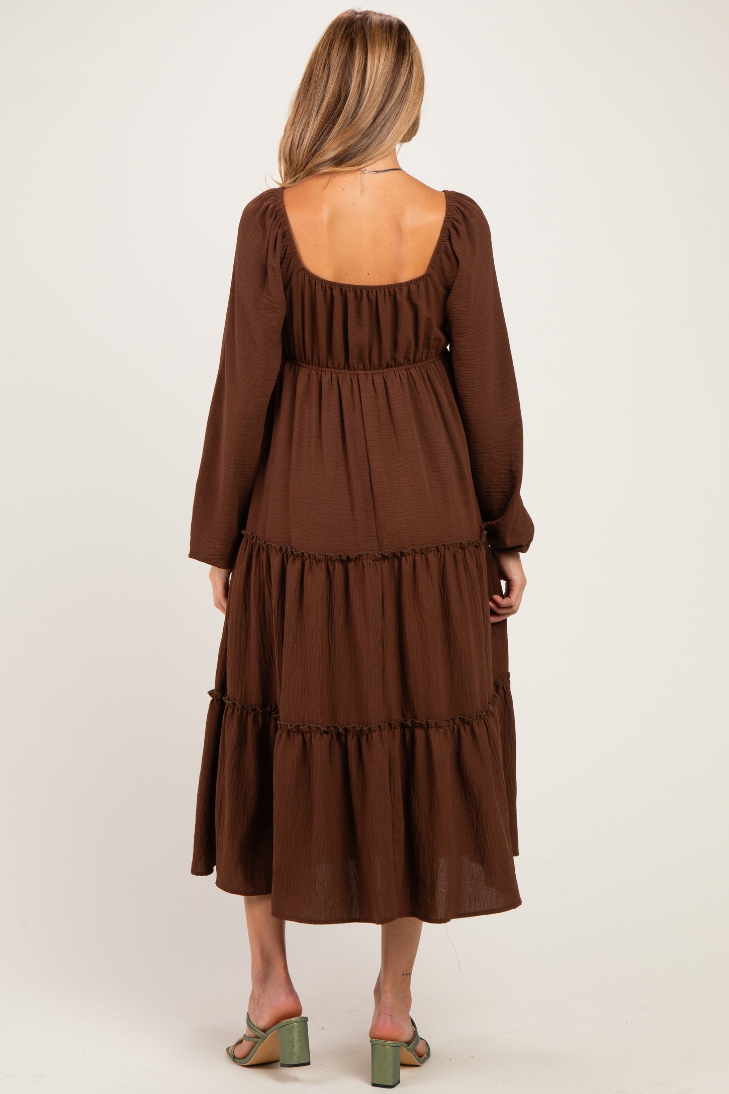 woman wearing a brown tiered maternity dress with long sleeves and a square neckline, showing the back view