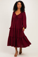 woman wearing a burgundy tiered maxi dress with a tie front and long sleeves