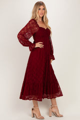 woman wearing a burgundy lace midi dress with long puff sleeves and a tiered skirt, standing in a side pose