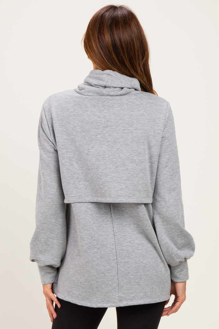 woman wearing a gray oversized sweatshirt with a cowl neck and layered back style, shown from the back