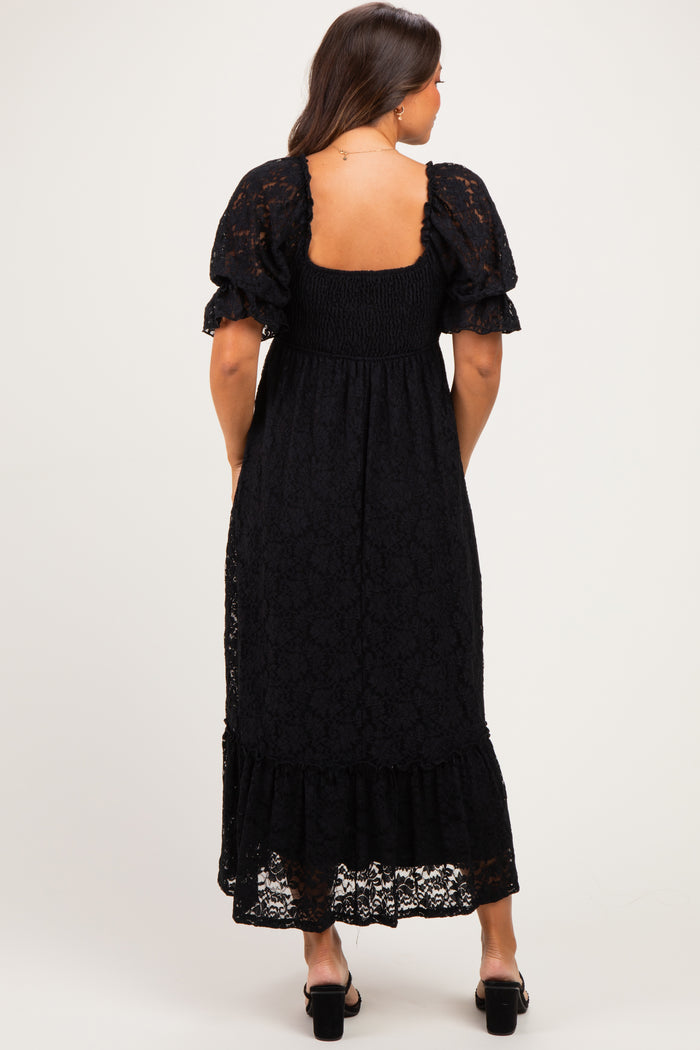 woman wearing a black lace maternity maxi dress with puff sleeves and a smocked bodice, showing a baby bump from the back
