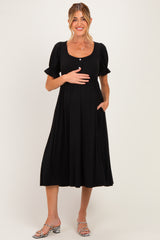 woman wearing a black maternity dress with short puff sleeves and a baby bump, showing side pockets