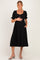 woman wearing a black maternity dress with short puff sleeves and a baby bump, showing side pockets