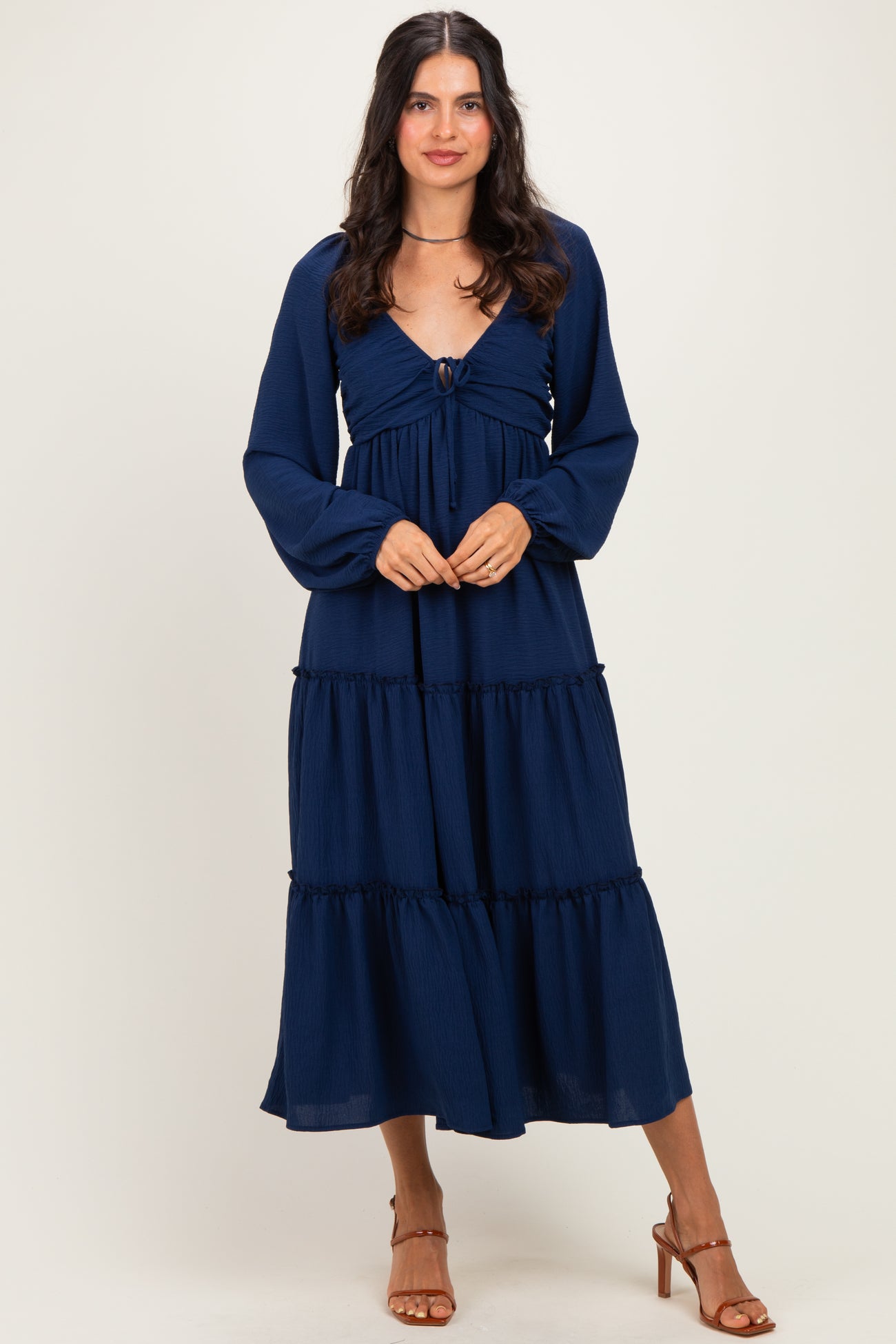 woman wearing a navy blue tiered maxi dress with long sleeves and a front tie detail