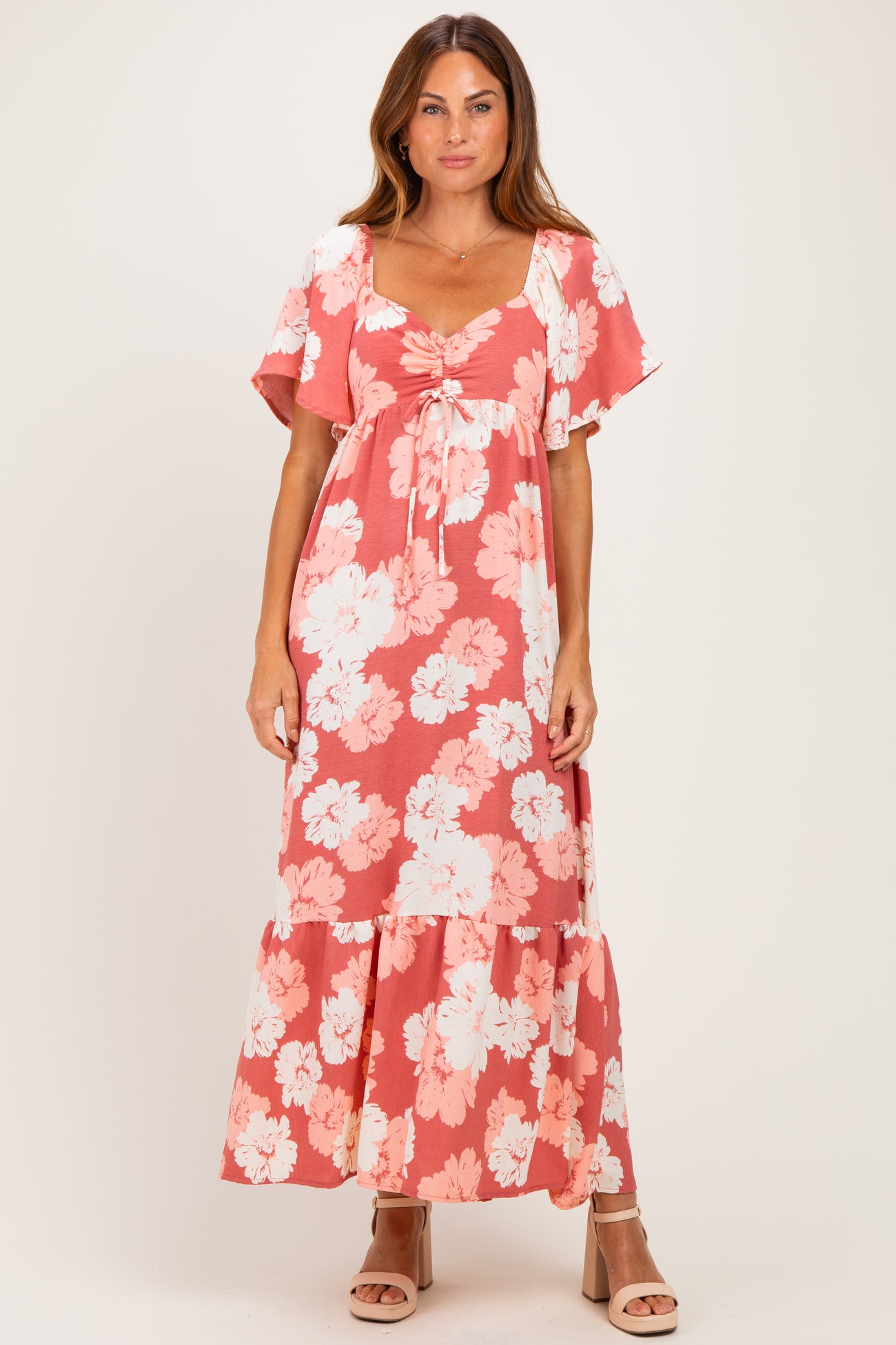 woman wearing a coral floral maxi dress with short sleeves and a tie-front detail