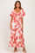 woman wearing a coral floral maxi dress with short sleeves and a tie-front detail