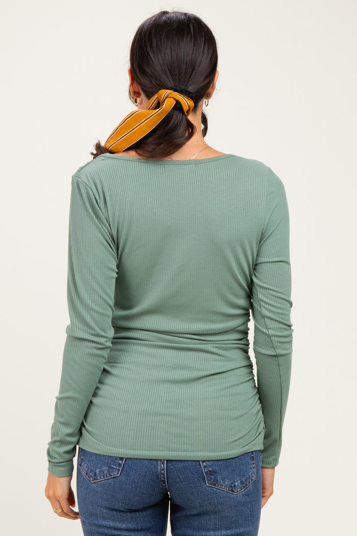 woman wearing a green ribbed long sleeve top with a scoop back and styled hair with a yellow scarf