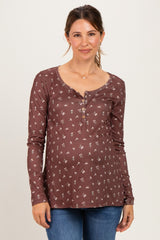 woman wearing a brown floral maternity top with a henley neckline and long sleeves, showing her baby bump