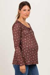 woman wearing a brown floral maternity top with buttons and a visible baby bump