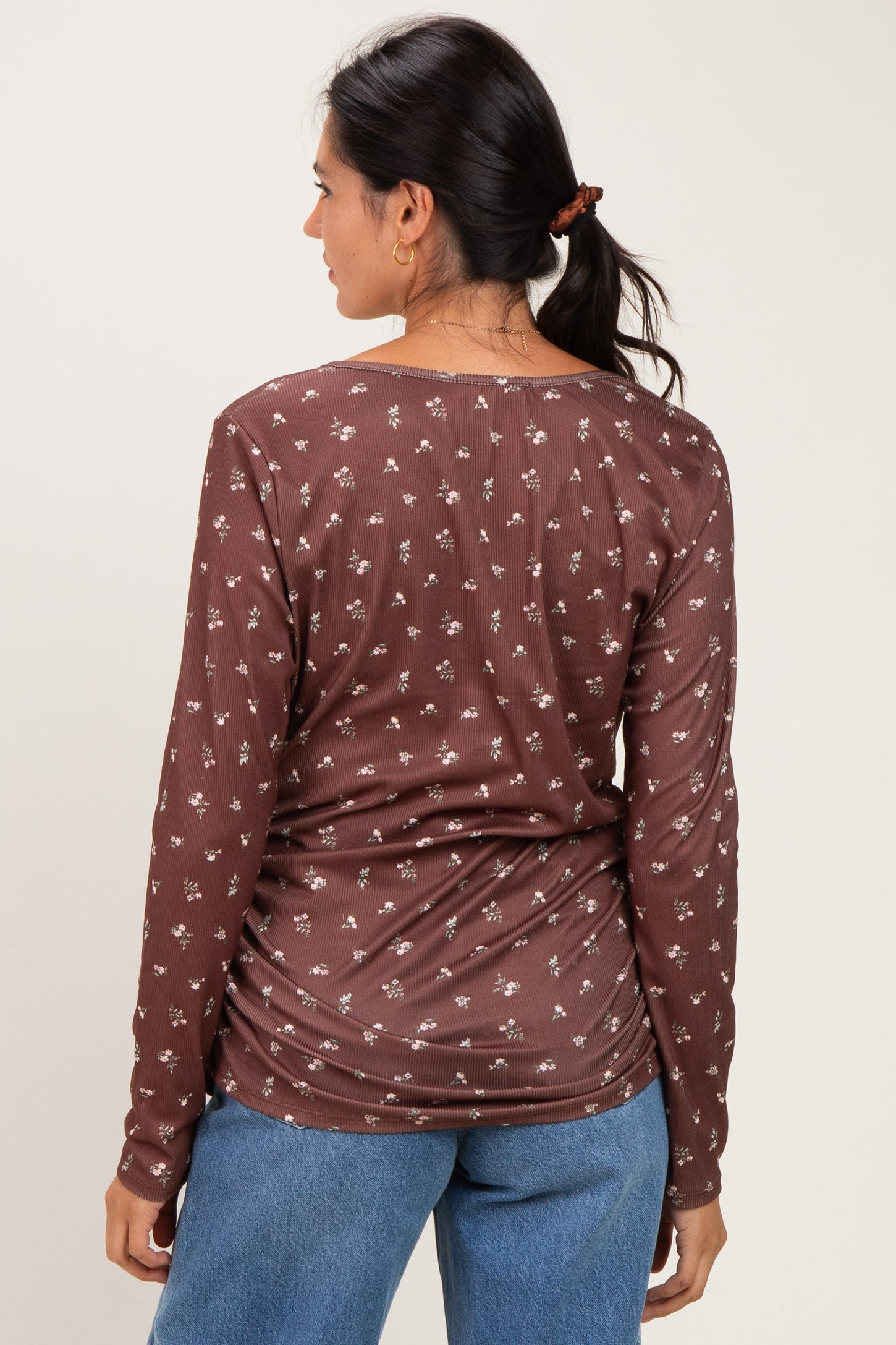 woman wearing a brown floral long sleeve top with a relaxed fit, seen from the back with gathered detail at the waist