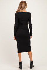 woman wearing a black long sleeve ribbed maternity dress, viewed from the back
