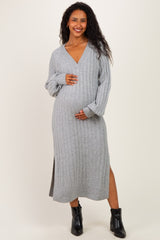 woman wearing a gray long sleeve maternity dress with a v-neckline and a side slit, holding her baby bump