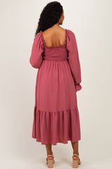 woman wearing a dusty rose maternity midi dress with puff sleeves and smocked bodice, showcasing a baby bump