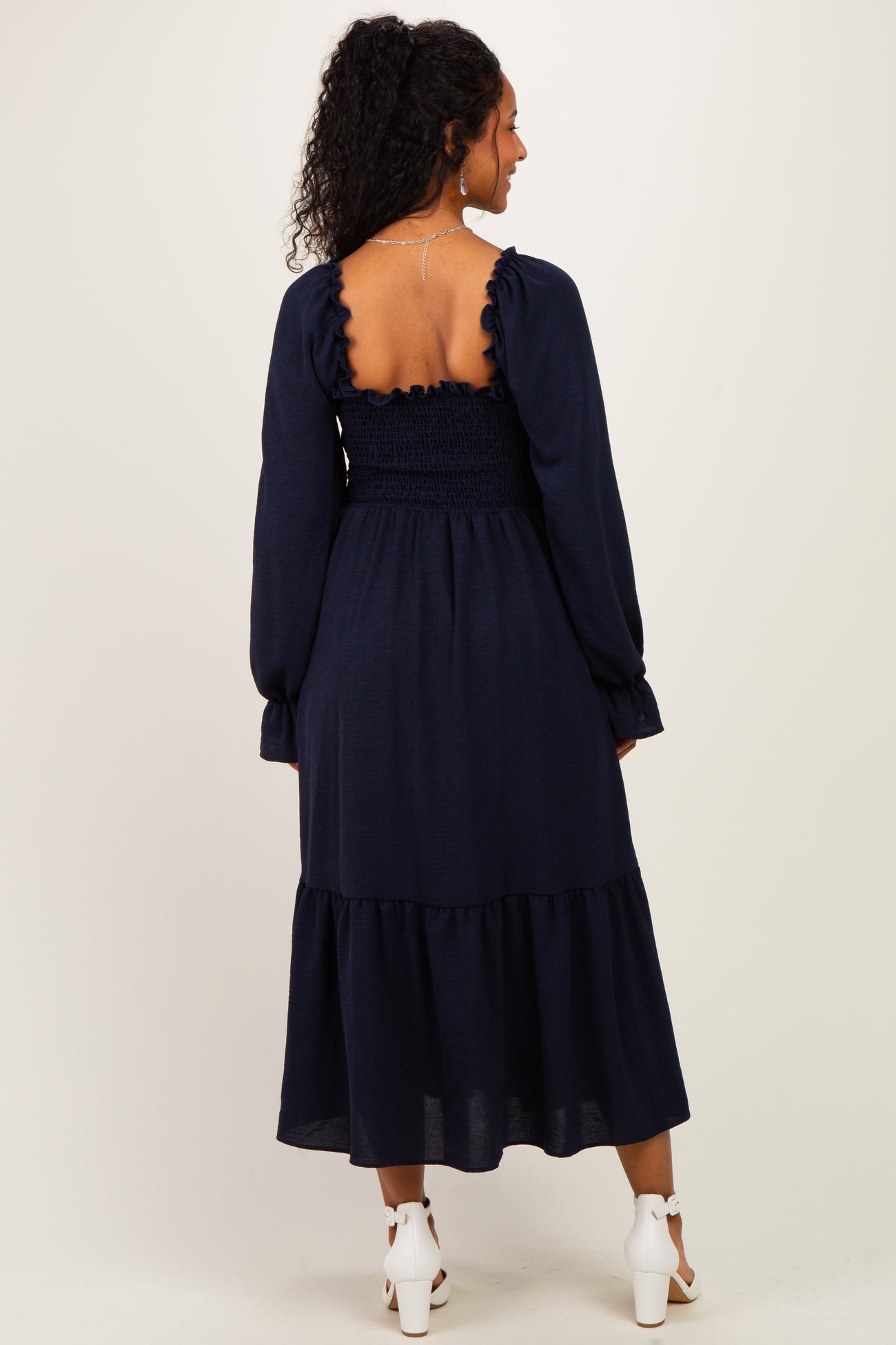 woman wearing a navy blue maternity dress with a smocked back and ruffled tiered hem
