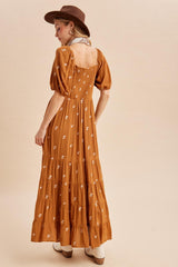 woman wearing a rust brown floral maxi dress with puff sleeves and a smocked back