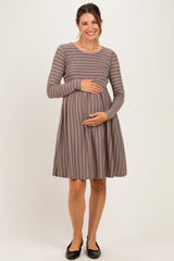 woman wearing a taupe and white striped long sleeve maternity dress and holding her baby bump