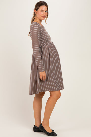 woman wearing a brown striped maternity dress with a fitted top and flared skirt, with a visible baby bump