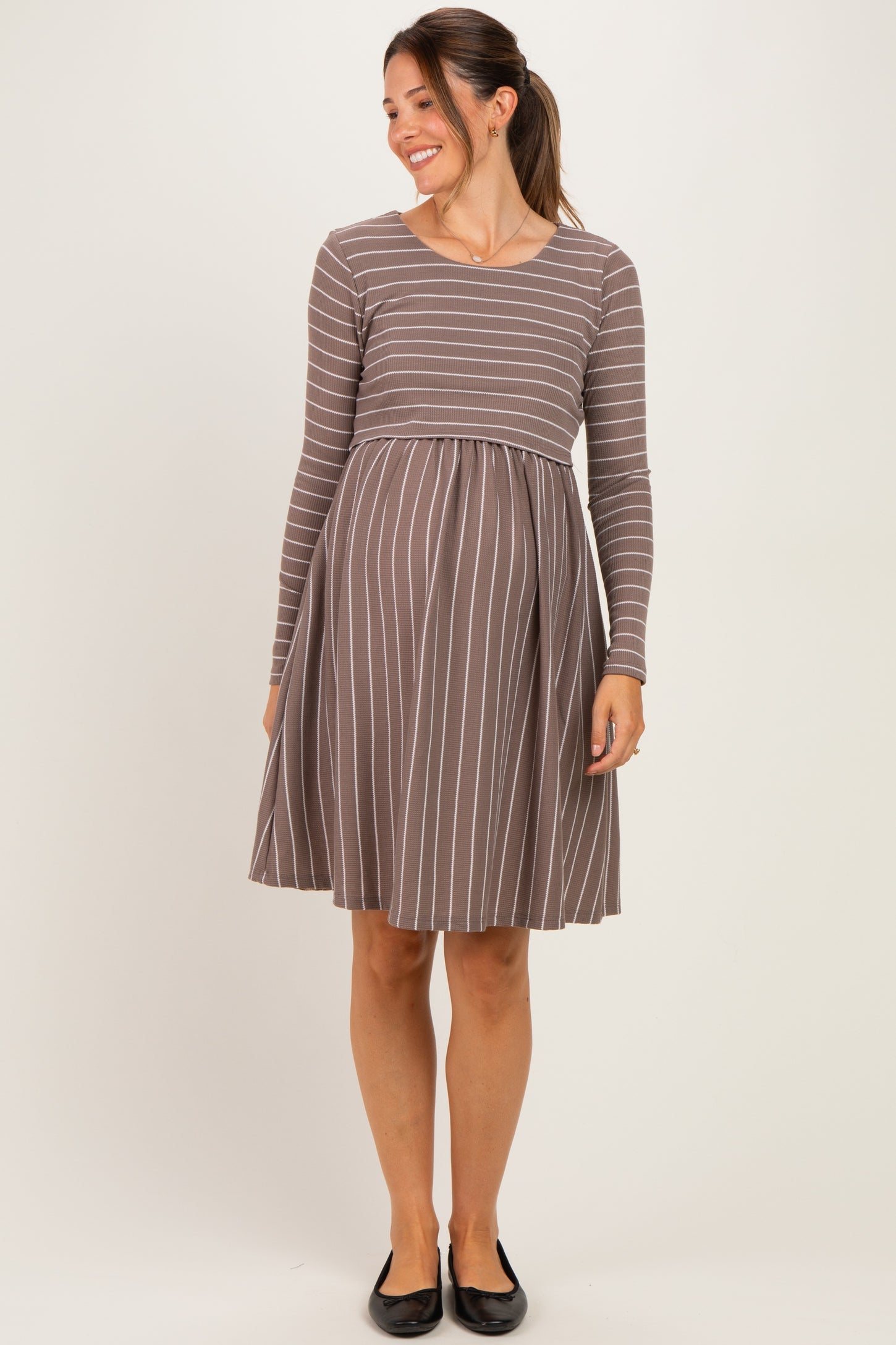 woman wearing a brown and white striped long sleeve maternity dress with a fitted bodice and flared skirt, baby bump visible