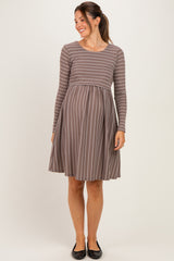 woman wearing a brown and white striped long sleeve maternity dress with a fitted bodice and flared skirt, baby bump visible